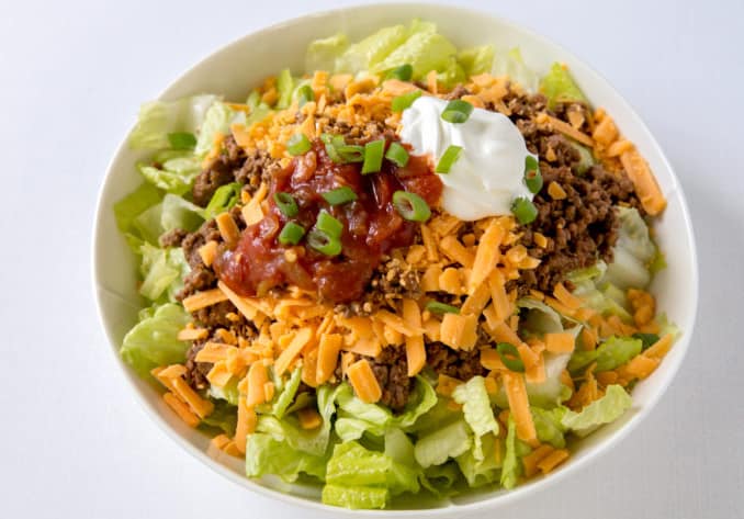 keto salad bowl filled with lettuce, ground beef, cheese, salsa, and sour cream